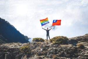 一位登山者在百岳巔峰揮舞旗幟，象徵透過時序調整策略，在熱門路線中成功避開人潮，享受高山獨行體驗的珍貴瞬間。